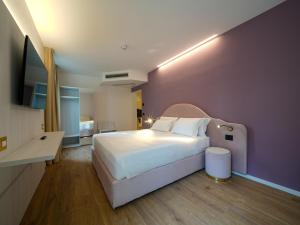 a bedroom with a white bed and a purple wall at Castiglioncello Suite in Castiglioncello