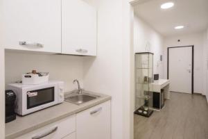 a white kitchen with a sink and a microwave at Airport Bari palese LUXURY 2 in Bari