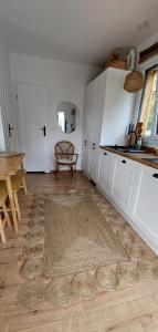 a kitchen with white cabinets and a rug on the floor at Domek DOMiarki in Klecza