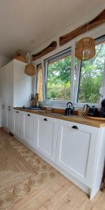 a kitchen with white cabinets and two windows at Domek DOMiarki in Klecza +64 photos