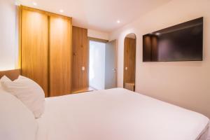 a bedroom with a white bed and a flat screen tv at Anna Suites Arpoador in Rio de Janeiro