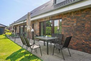 西代希施特里希Moderne KüstenHyggen mit Garten&Parkplatz - Hermannliving的庭院配有桌椅和遮阳伞