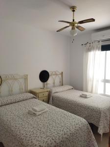 ein Schlafzimmer mit zwei Betten und einem Deckenventilator in der Unterkunft PUERTA MARINA in La Redondela