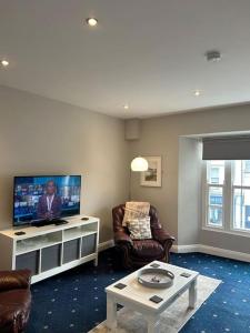 a living room with a flat screen tv and chairs at No 12 Bridge Street - Town Centre Apartment in Westport