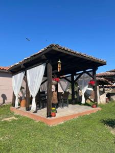 a wooden gazebo with white drapes at Къща за гости РАЙ 10човека in Boykovtsi