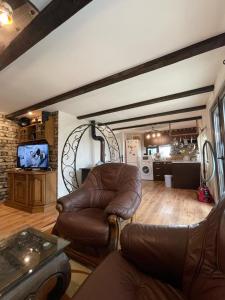 a living room with a leather chair and a tv at Къща за гости РАЙ 10човека in Boykovtsi