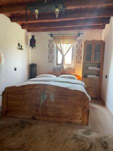a large wooden bed in a room with a window at Къща за гости РАЙ 10човека in Boykovtsi +26 photos