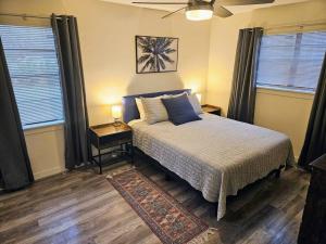 a bedroom with a bed and two windows and a rug at Madrona's Cottage A in Charleston