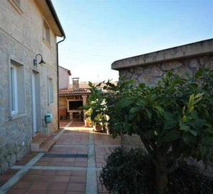 una passerella di mattoni tra due edifici con un albero di Casa das Roma a Cambados