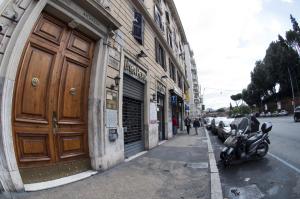 ローマにあるCasavamicaの大きな木製のドアがある建物の前に停められたオートバイ