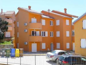 an orange building with cars parked in front of it at Apartmani Kvesic - Azzurro in Šilo