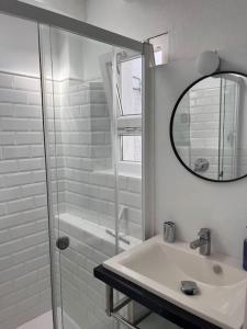 een witte badkamer met een wastafel en een spiegel bij Preciosa casa con terraza in Vejer de la Frontera