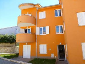 an orange building with white doors and windows at Apartmani Kvesic - Azzurro in Šilo