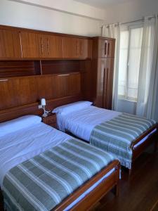two beds in a bedroom with wooden cabinets at Atxitxin in Mutriku
