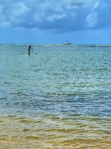 a man standing on a paddle board in the ocean at Pousada Villa Tainá - Arraial d'Ajuda, Bahia in Arraial d'Ajuda +70 photos