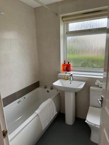 a white bathroom with a tub and a sink at Cozy 2 Bedroom Cottage in Kirkcaldy in Fife