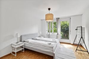 ein weißes Schlafzimmer mit einem Bett und einem Fenster in der Unterkunft Spacious Apartment in Zurich in Zürich