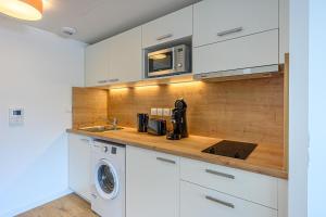een keuken met witte kasten en een wasmachine en droger bij OVELIA Fouesnant - Les Allées de Kervihan in Fouesnant