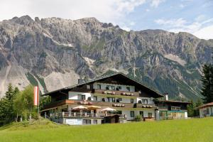 un edificio su una collina con montagne sullo sfondo di Kraftplatz am Dachstein - Herold - für Ruhesuchende und sportlich Aktive a Ramsau am Dachstein