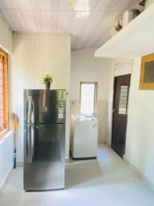 a kitchen with a refrigerator and a washer and dryer at Mampilly Guest House in Kottayam