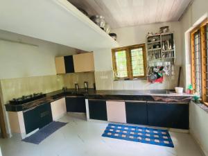 a kitchen with black and white counters and a sink at Mampilly Guest House in Kottayam