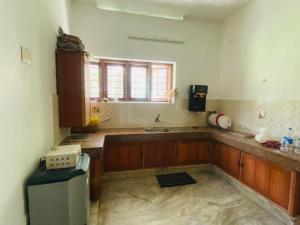 a kitchen with wooden cabinets and a sink and a window at Mampilly Guest House in Kottayam