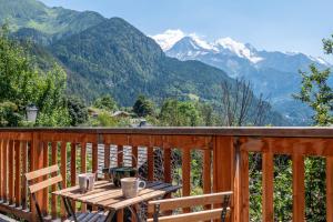 una terraza de madera con mesa, sillas y montañas en Le Mont Farm, en Servoz