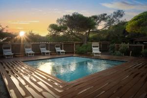 a swimming pool with chairs on a wooden deck at Sunset Villa in Castiglione della Pescaia