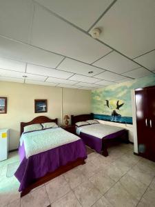 a bedroom with two beds and a painting on the ceiling at Nelyza's Suites & Adventure in Puerto Ayora