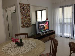 uma sala de estar com uma mesa e uma televisão em Apartamento 2 Quartos Vista Mar em Ubatuba