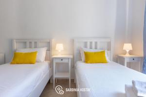 two white beds with yellow pillows in a room at Living Villanova Apartment in Cagliari