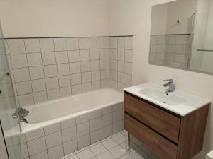 a bathroom with a sink and a bath tub and a mirror at T3 Macon Centre Rambuteau in Mâcon