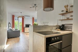 a kitchen with a stove top oven next to a living room at Oiseaux du Paradis in Amélie-les-Bains-Palalda