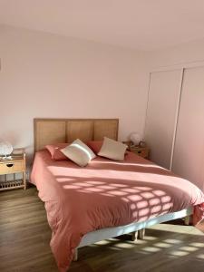 Schlafzimmer mit einem Bett mit rosa Bettwäsche und weißen Kissen in der Unterkunft Duplex T3 avec jardin, bord de mer et parking in Six-Fours-les-Plages + 12 Fotos