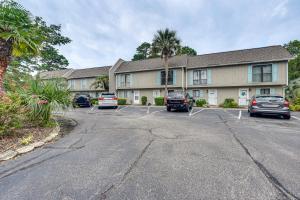 Un edificio con coches aparcados en un estacionamiento. en Patio and Pool Access North Myrtle Beach Retreat!, en Myrtle Beach