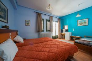 a blue bedroom with a large bed with an orange blanket at Ο Ξενώνας της Κατερίνας in Pavliani