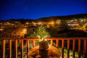 a table on a deck with a view of a town at night at Ο Ξενώνας της Κατερίνας in Pavliani