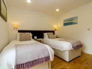 Habitación con 2 camas, paredes blancas y suelo de madera. en Maple, en Truro