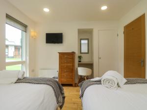 Un dormitorio con dos camas y un televisor en la pared. en Hazel, en Truro