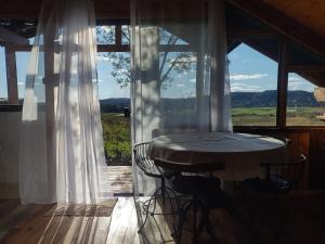 a table and chairs on a porch with a large window at Na'raucária in Cambará