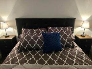 a bed with two lamps and a blue pillow on it at Cozy New 1 bed basement suite in Edmonton
