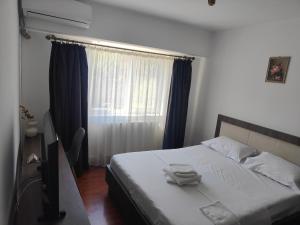 a bedroom with a bed and a window with blue curtains at Mari's By The Sea in Mangalia