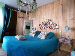 a bedroom with a blue bed with a wooden wall at le Relais de la Cavayere - Chambres d'hôtes avec SPA & SAUNA Carcassonne - Parking privé ferme in Carcassonne