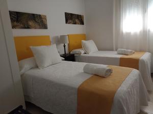 ein Hotelzimmer mit zwei Betten mit Handtüchern darauf in der Unterkunft Piso vacacional en Sanlúcar in Sanlúcar de Barrameda