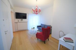a living room with a red chair and a chandelier at Acropolis Hill House in Athens