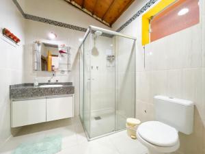 a bathroom with a shower and a toilet and a sink at Chalés Lá na Roça in Gonçalves +59 photos