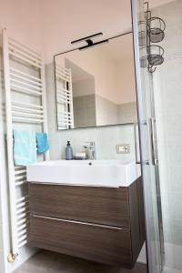 ein Badezimmer mit einem weißen Waschbecken und einem Spiegel in der Unterkunft IL CAMPANILE Apartment in Omegna