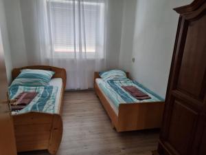 two beds in a small room with a window at Ferienwohnung 2 mit 3 Schlafzimmer und Garten in Crailsheim +3 photos