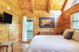 a bedroom in a log cabin with a bed and a tv at Charming 2BR Cabin with Hot Tub & Mountain Views in Sevierville