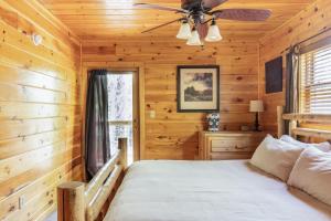 a log cabin bedroom with a bed and a ceiling fan at Charming 2BR Cabin with Hot Tub & Mountain Views in Sevierville